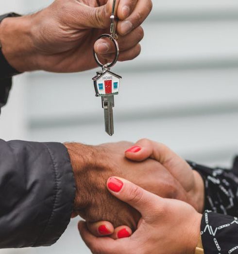 Client Trust - Close-up of a realtor handing over a house key to a new homeowner, symbolizing ownership and investment.