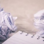 Rejection - Crumpled papers scattered around a notepad, symbolizing creative process and ideas.