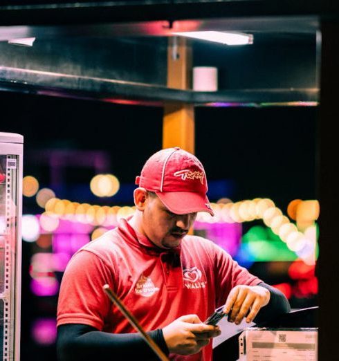 Sales Scripts - A man preparing ice cream cones at a nighttime illuminated booth with colorful lights.