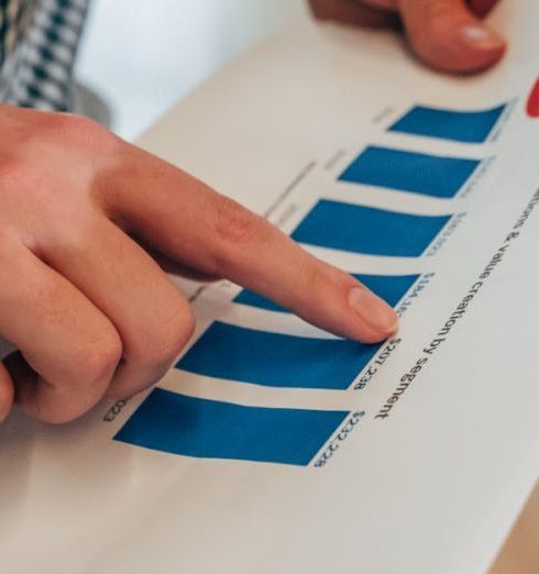 Sales Performer - Close-up of hands pointing at a bar chart on paper, analyzing financial stats and report.