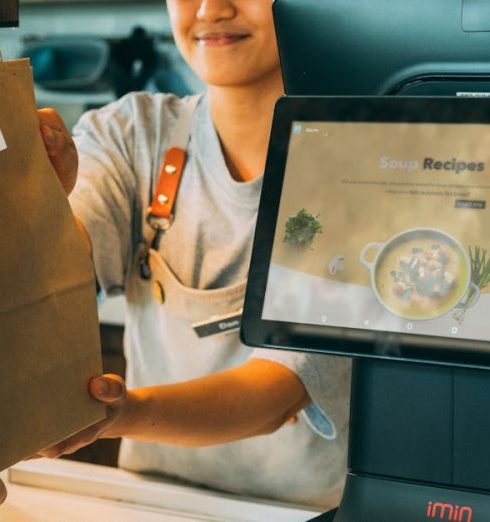 Customer Pain Points - A smiling cashier hands a paper bag to a customer at a modern point of sale, showcasing customer service.