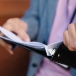 Follow-Up - Person flipping through documents in a binder, showcasing organization and focus.