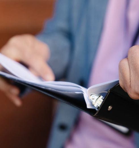 Follow-Up - Person flipping through documents in a binder, showcasing organization and focus.