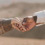 Bonds - Romantic couple holding hands in the Agafay Desert, capturing love and connection on a sunny day.