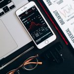 Risk Analysis - Top view of financial tools including a laptop, smartphone with stock data, and charts for market analysis.