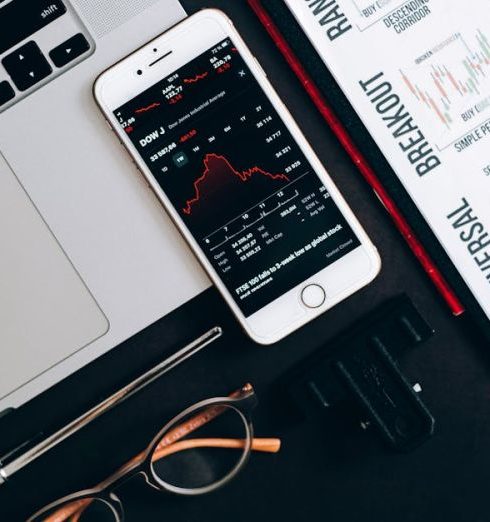 Risk Analysis - Top view of financial tools including a laptop, smartphone with stock data, and charts for market analysis.