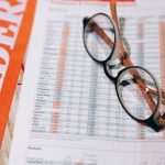 Mutual Funds - Close-up of financial documents with eyeglasses, depicting data analysis and business insights.