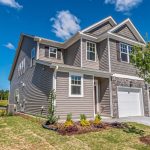 Real Estate Markets - Beautiful modern house with manicured lawn under a clear blue sky.