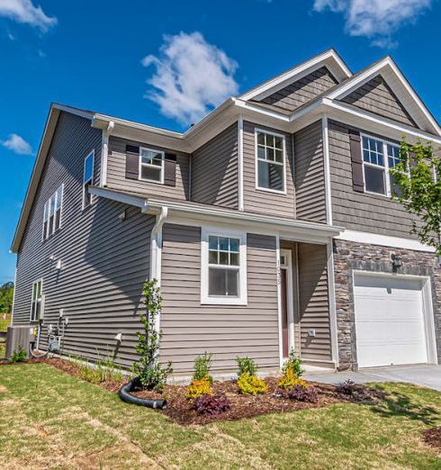 Real Estate Markets - Beautiful modern house with manicured lawn under a clear blue sky.