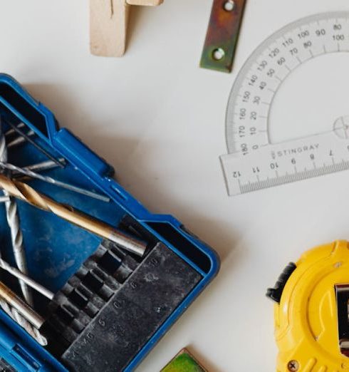 Small Businesses - A selection of carpentry tools including drill bits, measuring tape, and protractor in an overhead shot.