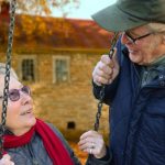 Retirement - A happy elderly couple sharing a joyful moment on a swing in autumn setting.