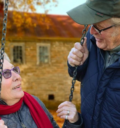 Retirement - A happy elderly couple sharing a joyful moment on a swing in autumn setting.