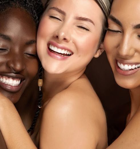 Bonds - Three diverse women embracing with eyes closed and smiling, celebrating friendship and unity.