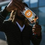 Investment Risks - A man burns a fake dollar with a Bitcoin symbol outdoors, symbolizing cryptocurrency risks.