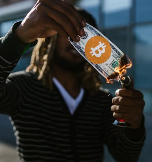 Investment Risks - A man burns a fake dollar with a Bitcoin symbol outdoors, symbolizing cryptocurrency risks.