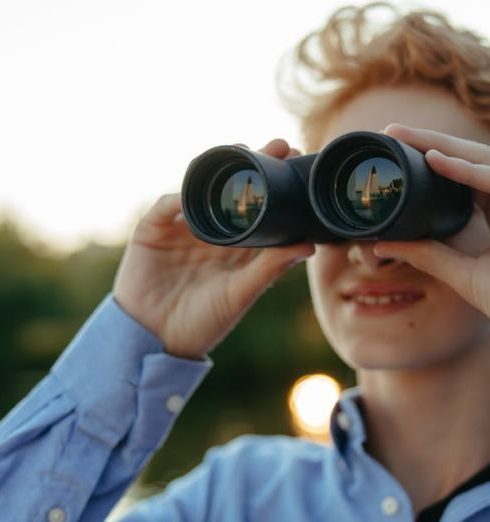 Long-Term Potential - A young person uses binoculars during a nature observation adventure.