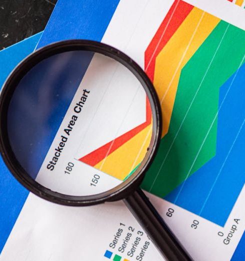 Blue-Chip Stocks - Magnifying glass highlighting stacked area charts for business analysis.