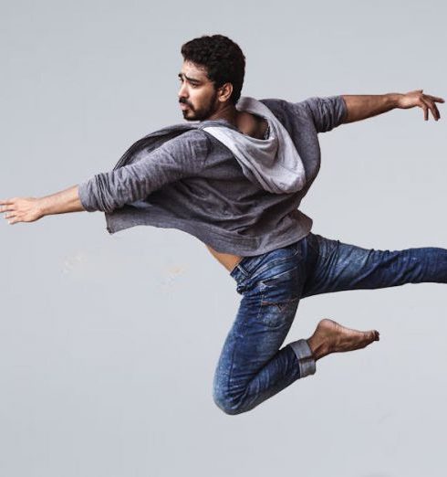 Performance - A male contemporary dancer in casual wear leaping gracefully in mid-air, showcasing agility and flexibility.