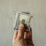 Index Funds - A clear view of a human hand holding a stack of US dollar bills, symbolizing finances.