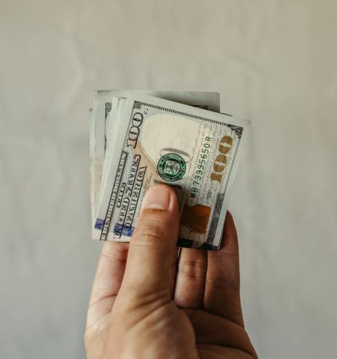 Index Funds - A clear view of a human hand holding a stack of US dollar bills, symbolizing finances.