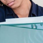 Responsibilities - A woman appears stressed while clutching files against a wall, depicting workplace anxiety.