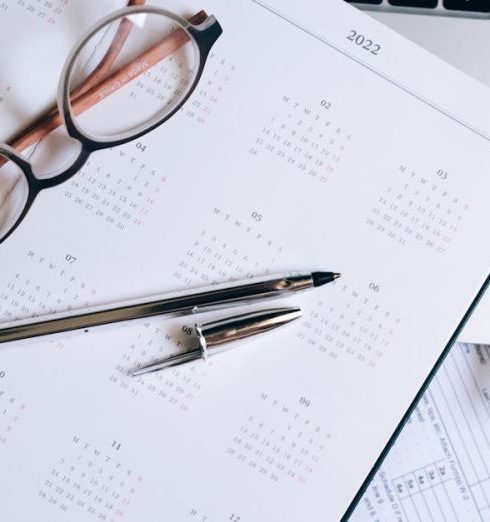 Performance Reviews - Overhead view of a desk with glasses, a pen, calendar, and tax documents.