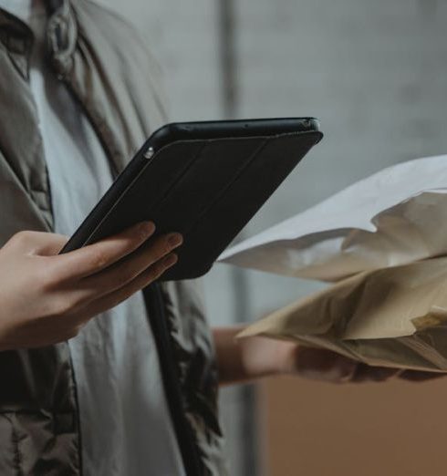 Management System - A person using a tablet to manage packages in an indoor setting, highlighting technology and logistics.