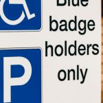 Inclusion Policy - A blue badge parking sign mounted on a wooden post indicating reserved parking for disabled access.