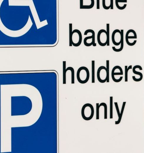 Inclusion Policy - A blue badge parking sign mounted on a wooden post indicating reserved parking for disabled access.