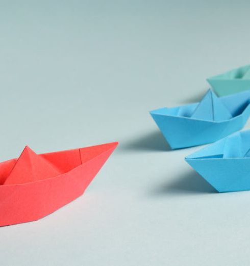 Leadership Development - Colorful origami paper boats arranged to depict leadership and teamwork concepts.