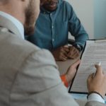 Feedback - A recruiter reviews a candidate's documents during a job interview in a modern office setting.