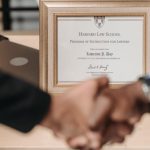 Recognition Programs - Harvard Law School degree with handshake representing achievement and professional agreement.