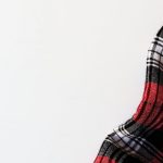 Background Checks - Close-up of red plaid flannel fabric on a white background, showcasing texture and pattern.