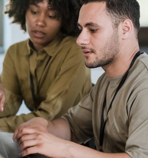 Inclusive Environment - Two colleagues working together on a laptop in a modern office setting.