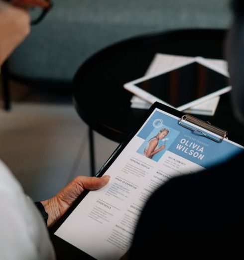 Talent Acquisition - Business professionals conducting an interview with resume on clipboard in an office setting.