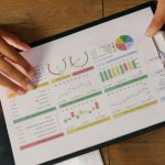 Performance Plans - Top view of hands holding a financial report with colorful graphs and charts, ideal for business presentations.