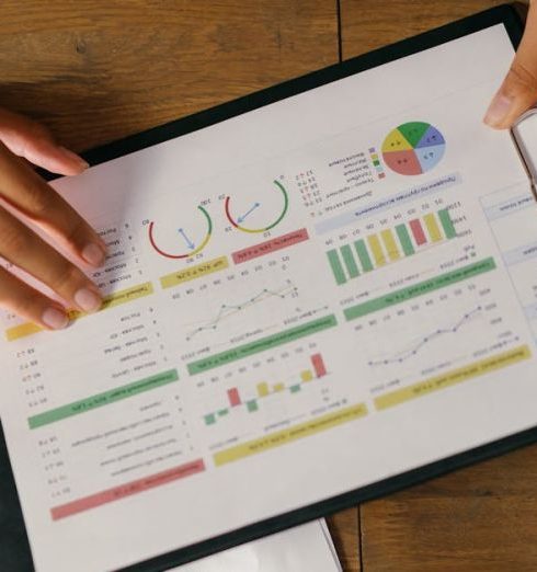 Performance Plans - Top view of hands holding a financial report with colorful graphs and charts, ideal for business presentations.