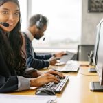 Diverse Workforce - Smiling call center agents in an office providing customer support on computers.