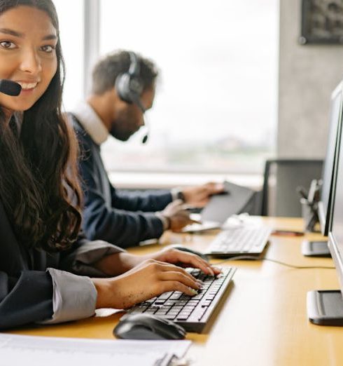 Diverse Workforce - Smiling call center agents in an office providing customer support on computers.