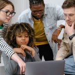 Business Goals - Diverse group of coworkers collaborating on a project using a laptop in a modern office.