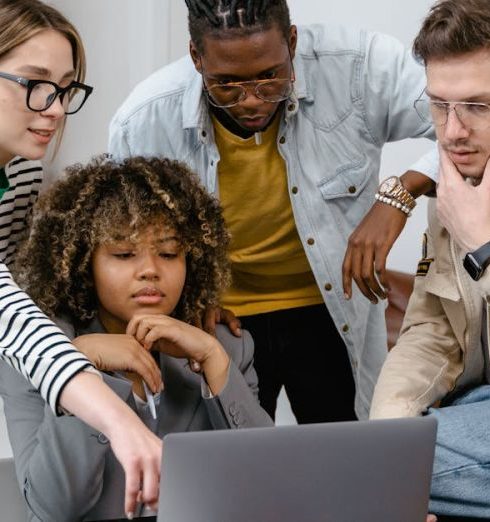 Business Goals - Diverse group of coworkers collaborating on a project using a laptop in a modern office.