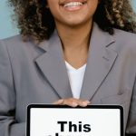 Vision Statement - Young woman smiling while holding a sign that reads 'This change everything'.