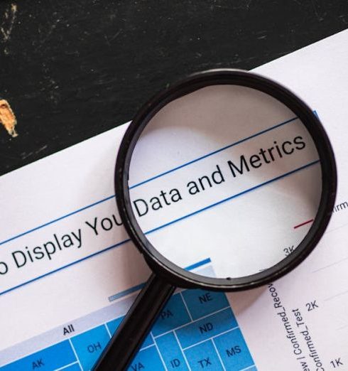 Metrics - Close-up of a magnifying glass over financial data charts and metrics on printed paper.