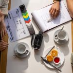 Planning Session - Aerial view of a team discussing a project with a clapperboard in a café setting.