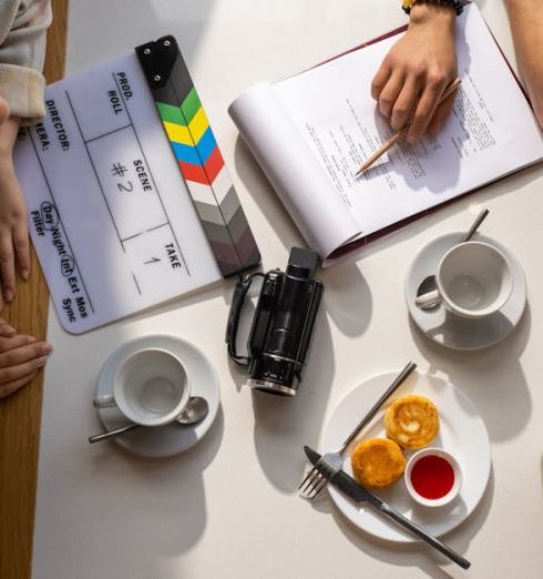 Planning Session - Aerial view of a team discussing a project with a clapperboard in a café setting.