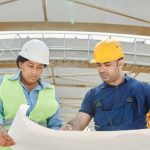 Planning Framework - Male and female engineers discussing blueprints at a construction site, promoting teamwork and planning.