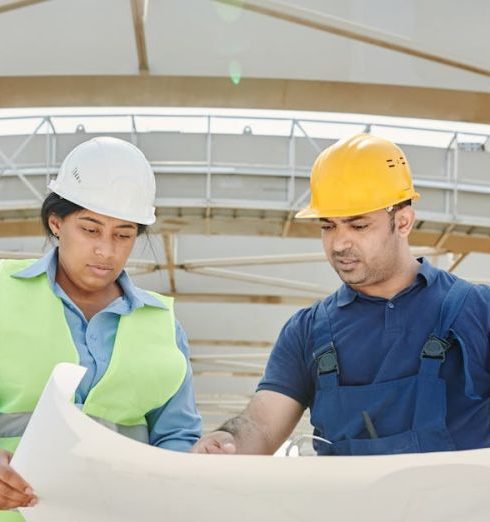 Planning Framework - Male and female engineers discussing blueprints at a construction site, promoting teamwork and planning.