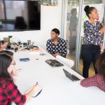 Collaboration - A multicultural office team engages in a collaborative brainstorming session around a conference table.