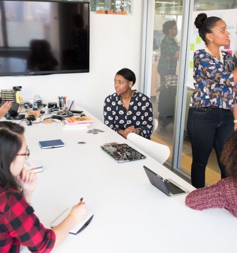 Collaboration - A multicultural office team engages in a collaborative brainstorming session around a conference table.