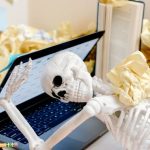 Deadlines - A skeleton surrounded by crumpled paper and books at a messy desk symbolizes burnout and overwork.